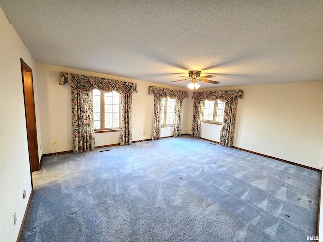 carpeted spare room with visible vents, plenty of natural light, a textured ceiling, and baseboards