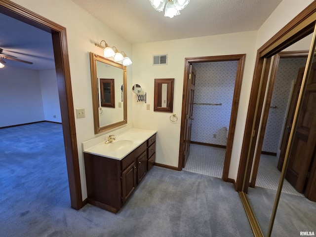 bathroom with baseboards, visible vents, a ceiling fan, a textured ceiling, and vanity