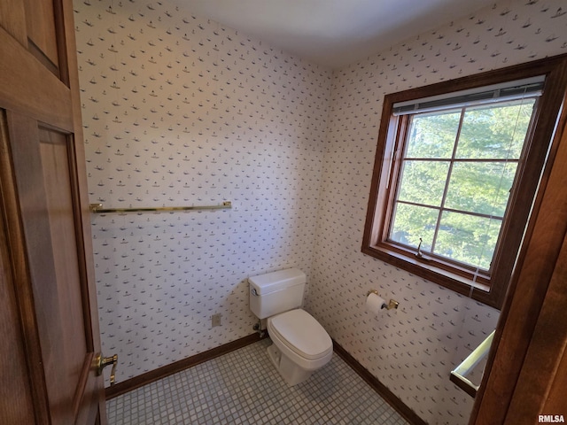 half bath featuring wallpapered walls, tile patterned flooring, toilet, and baseboards