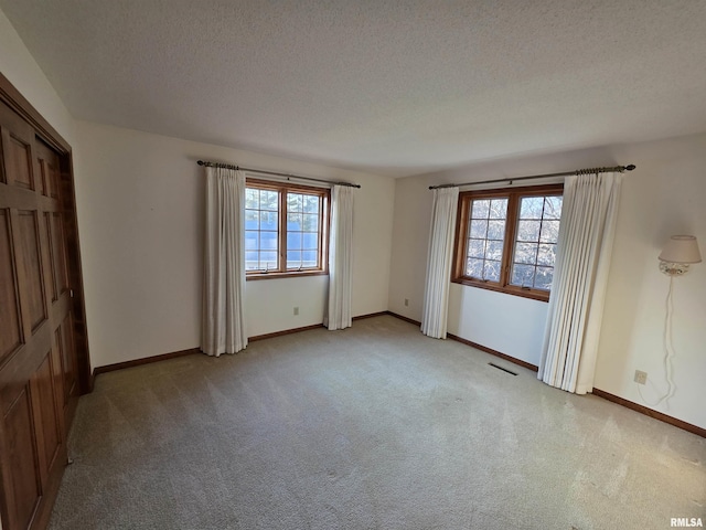 interior space with visible vents, light carpet, a textured ceiling, and baseboards