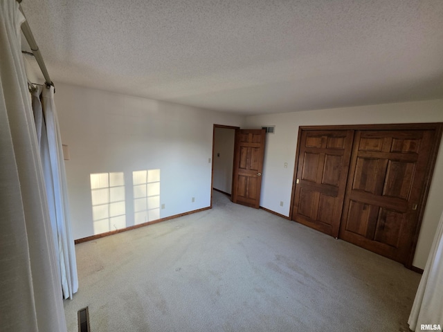 unfurnished bedroom with light carpet, a textured ceiling, visible vents, and baseboards