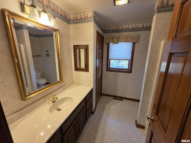 bathroom with visible vents, toilet, vanity, baseboards, and wallpapered walls