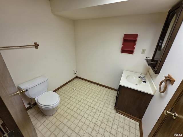 half bathroom featuring toilet, baseboards, and vanity