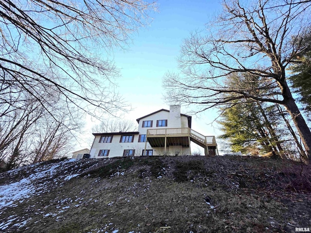 back of house with a chimney and a deck