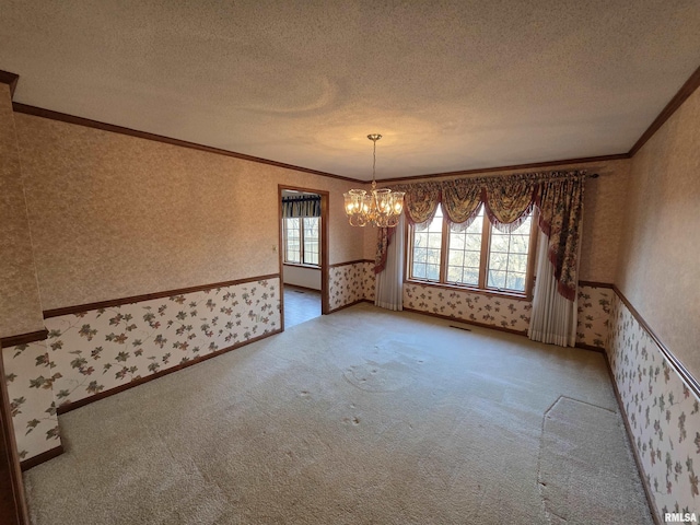 carpeted empty room with a textured ceiling, crown molding, and wallpapered walls