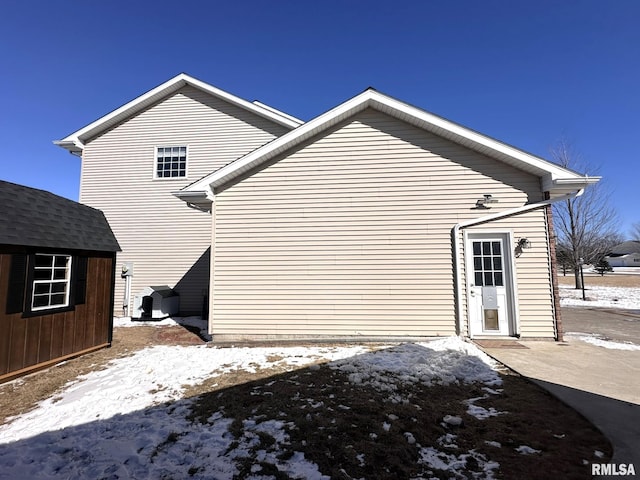 view of snow covered exterior featuring a storage shed and an outbuilding