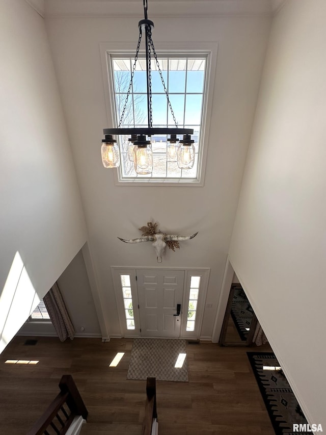 entryway featuring an inviting chandelier, a high ceiling, baseboards, and wood finished floors