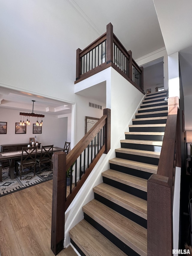 stairs featuring crown molding, visible vents, and wood finished floors