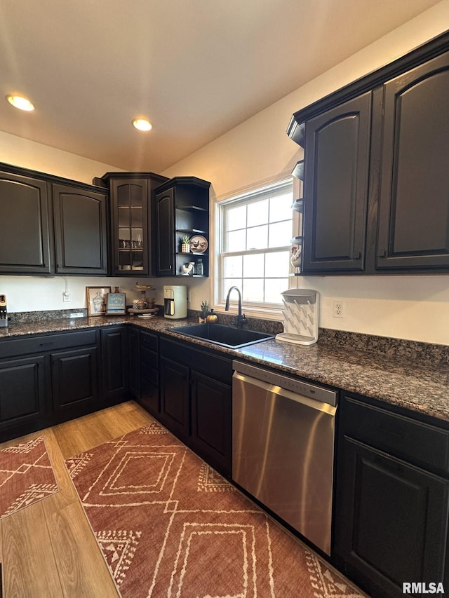 kitchen featuring a sink, light wood-style floors, dishwasher, open shelves, and dark countertops