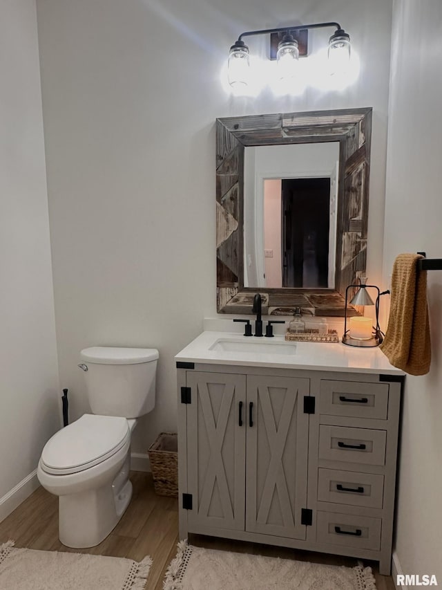 bathroom with baseboards, vanity, toilet, and wood finished floors