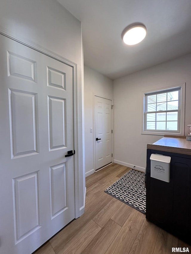 doorway with light wood-type flooring and baseboards