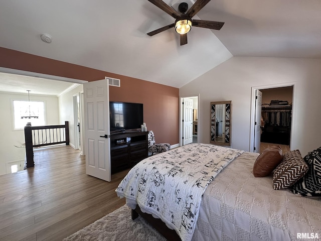 bedroom with lofted ceiling, visible vents, wood finished floors, baseboards, and ceiling fan with notable chandelier