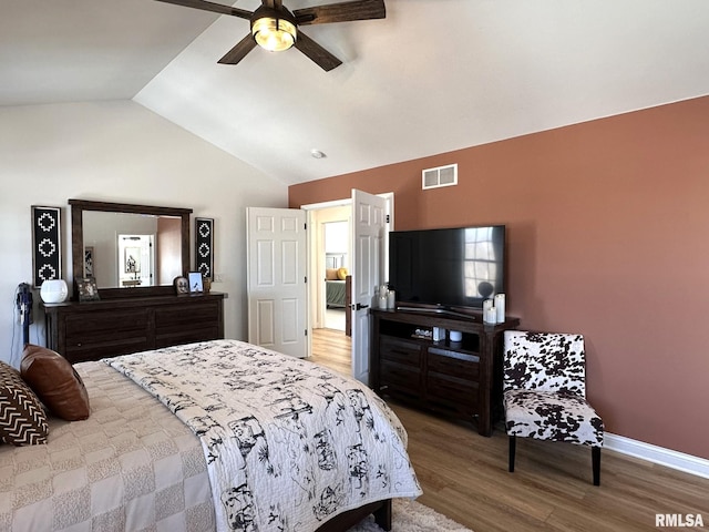 bedroom featuring wood finished floors, a ceiling fan, visible vents, vaulted ceiling, and baseboards