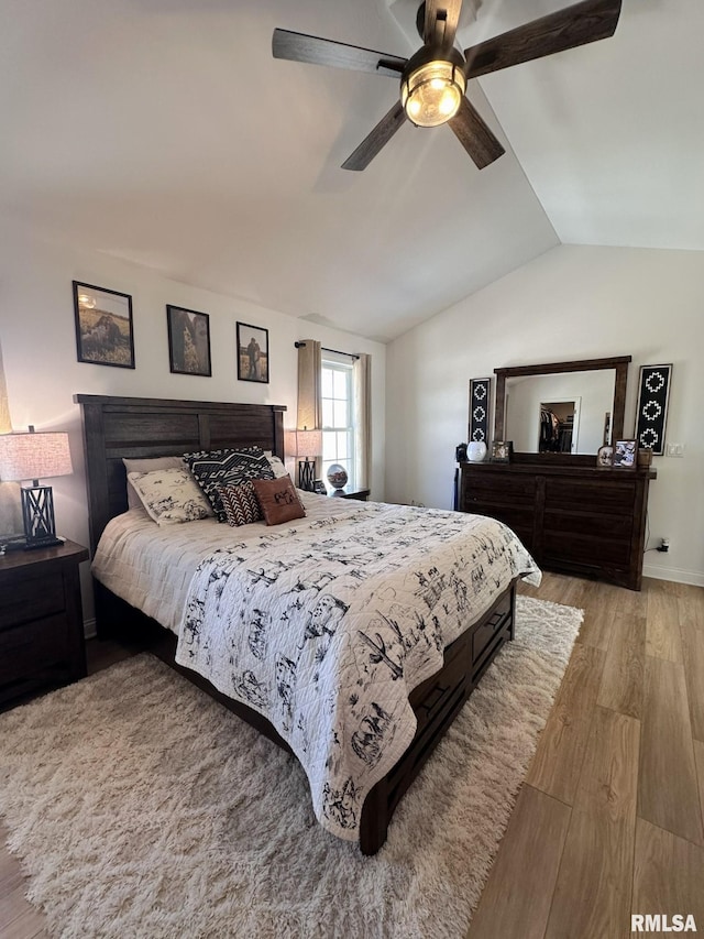 bedroom featuring light wood-type flooring, vaulted ceiling, and a ceiling fan