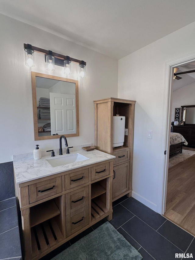 ensuite bathroom featuring ceiling fan, tile patterned flooring, connected bathroom, vanity, and baseboards