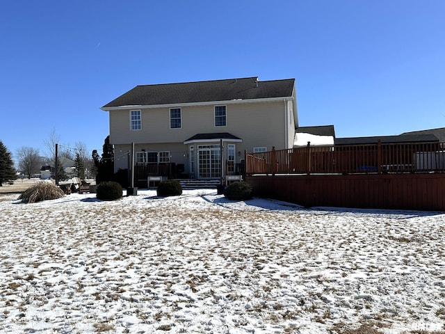 snow covered back of property with a wooden deck