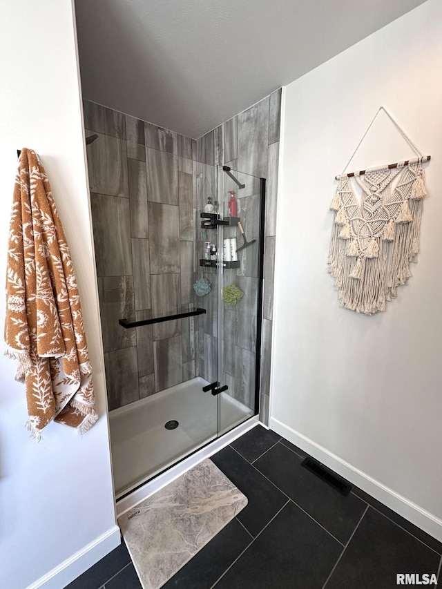 full bathroom featuring tiled shower, visible vents, baseboards, and tile patterned floors