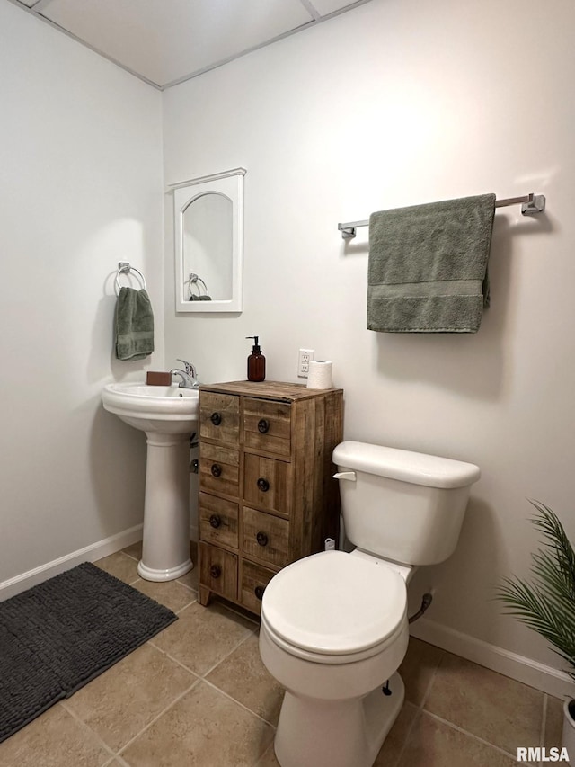 half bathroom with baseboards, toilet, and tile patterned floors