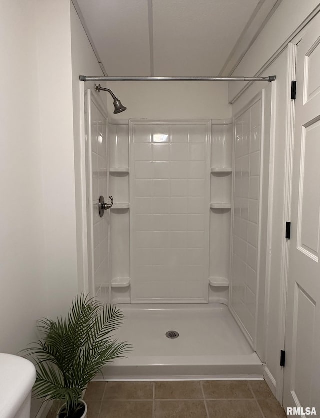 full bathroom featuring tile patterned flooring, a shower stall, and toilet