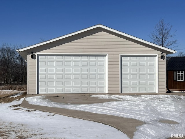 snow covered garage with a detached garage