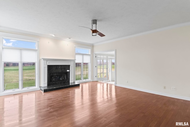 unfurnished living room featuring wood finished floors, crown molding, baseboards, and a premium fireplace