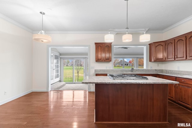 kitchen with ornamental molding, a center island, pendant lighting, and stainless steel gas stovetop