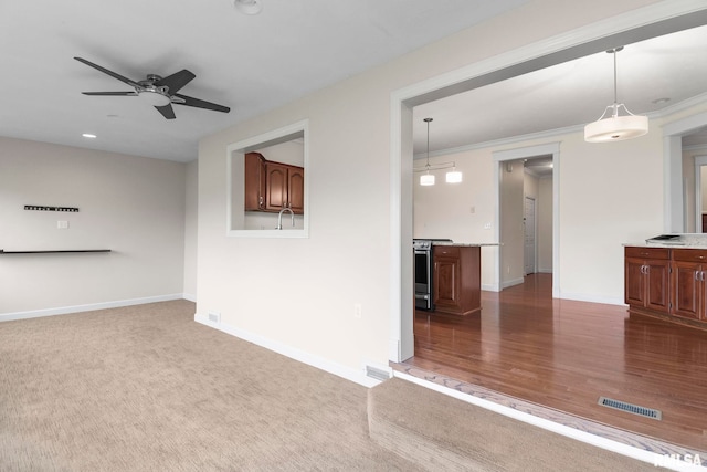 interior space featuring visible vents, baseboards, a ceiling fan, crown molding, and dark carpet