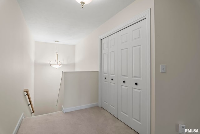 hallway with baseboards, an upstairs landing, and light colored carpet