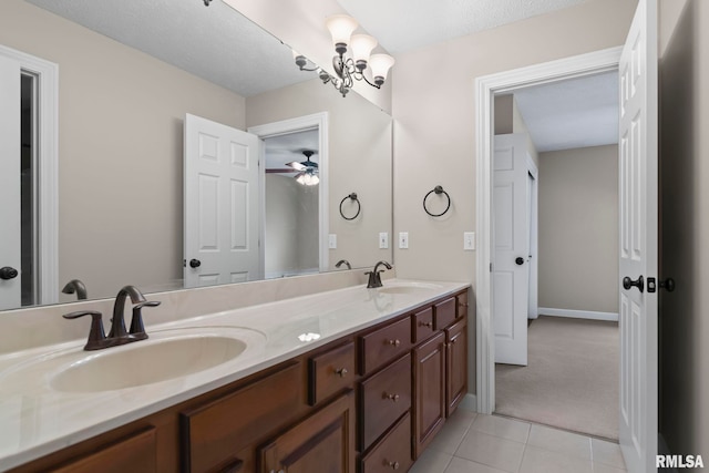 bathroom featuring double vanity, tile patterned flooring, a sink, and baseboards