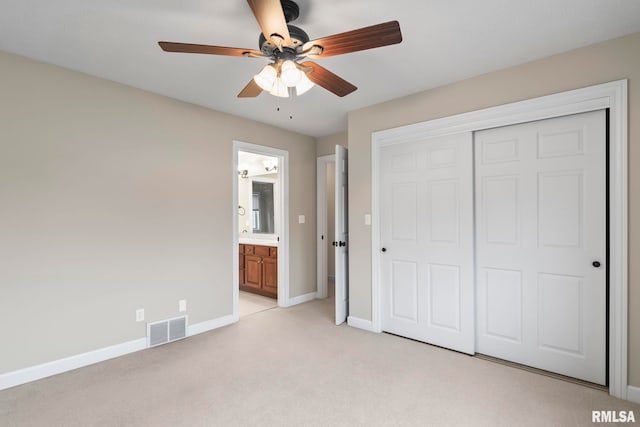 unfurnished bedroom with light carpet, visible vents, baseboards, a closet, and ensuite bath