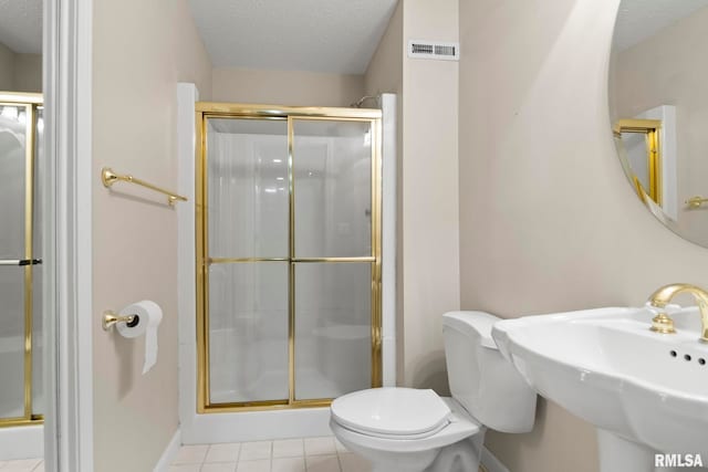 bathroom featuring a sink, a stall shower, toilet, and a textured ceiling