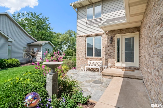 property entrance featuring brick siding and a patio