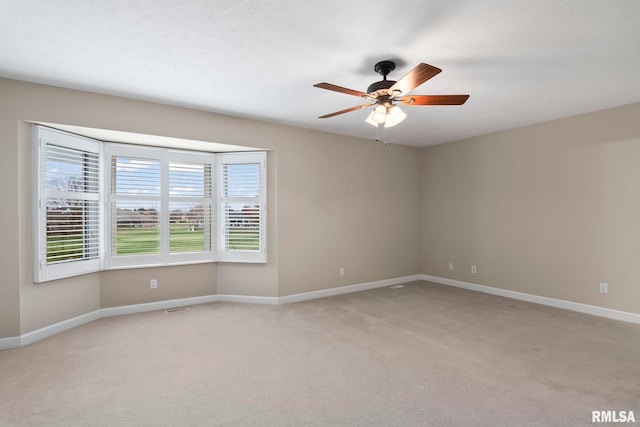 empty room featuring baseboards, a ceiling fan, and light colored carpet