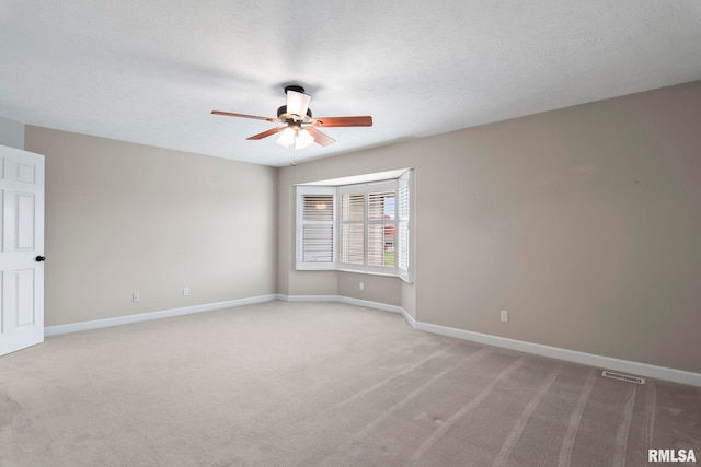 unfurnished room featuring a textured ceiling, carpet floors, a ceiling fan, visible vents, and baseboards