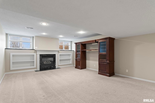 unfurnished living room with light carpet, a textured ceiling, and baseboards