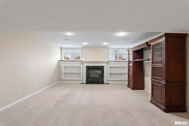 unfurnished living room with baseboards, a premium fireplace, plenty of natural light, and light colored carpet