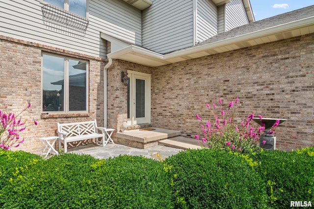 view of exterior entry featuring a patio and brick siding