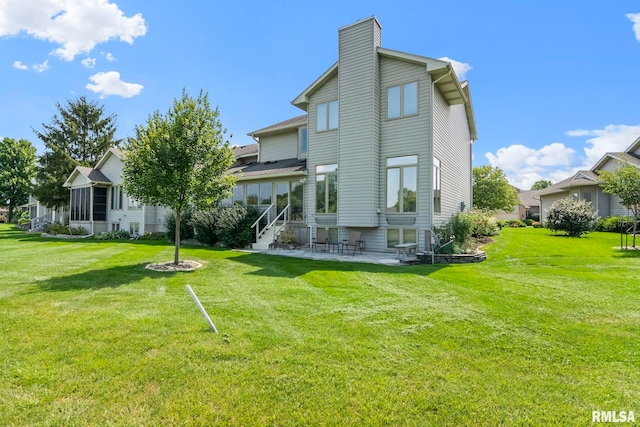 rear view of property with a yard, a chimney, and a patio