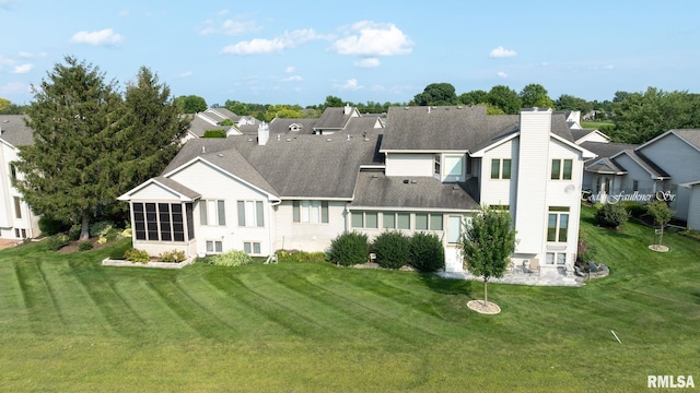 rear view of house featuring a residential view, a sunroom, a yard, and a chimney