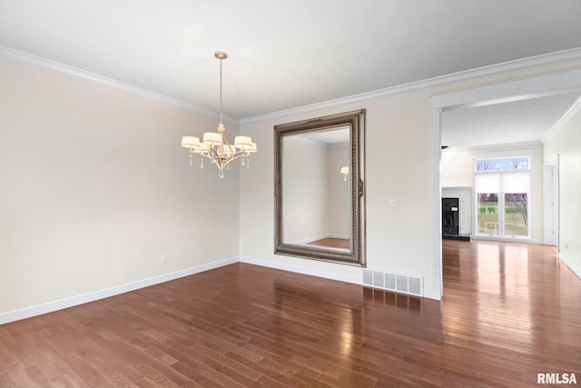 empty room with baseboards, visible vents, dark wood-type flooring, an inviting chandelier, and crown molding