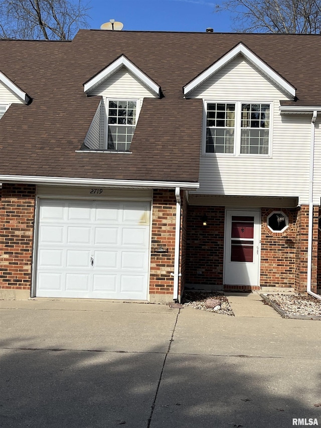 view of property featuring a garage, roof with shingles, concrete driveway, and brick siding