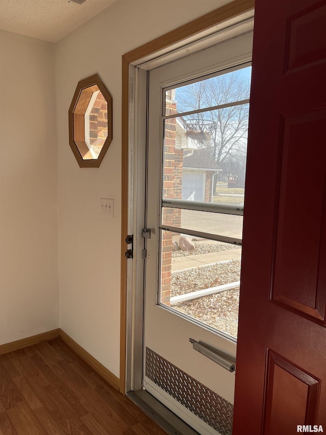 doorway featuring wood finished floors and baseboards