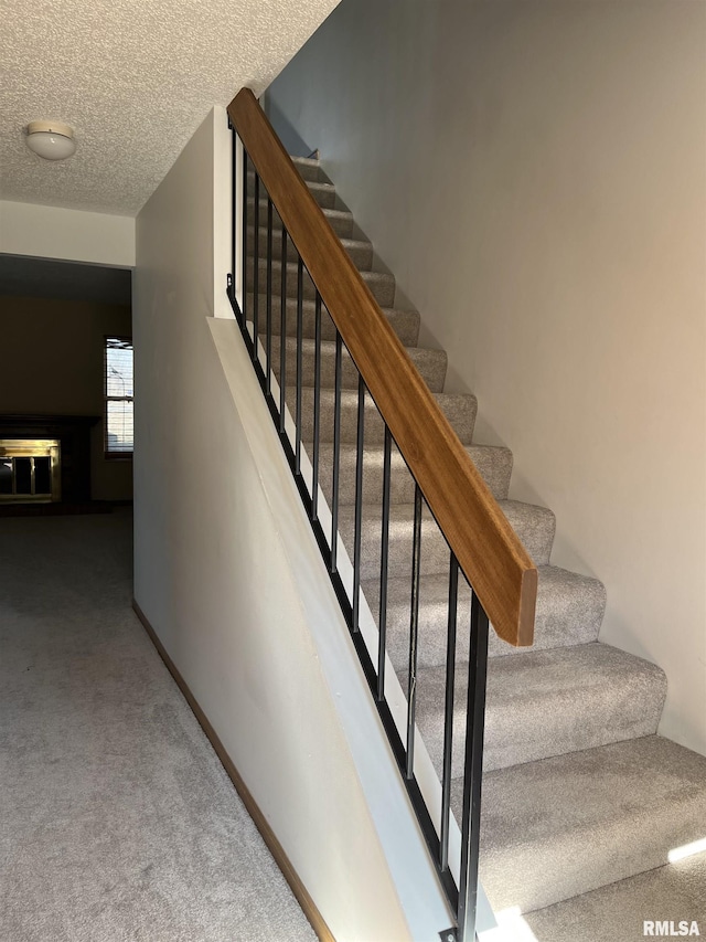 stairs featuring carpet, baseboards, and a textured ceiling