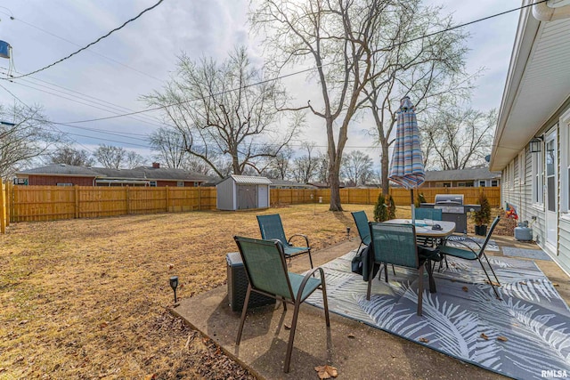 view of yard with a storage shed, a patio, a fenced backyard, an outdoor structure, and outdoor dining space