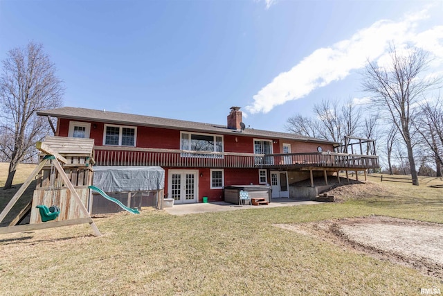 back of house featuring french doors, a playground, a chimney, a hot tub, and a patio area