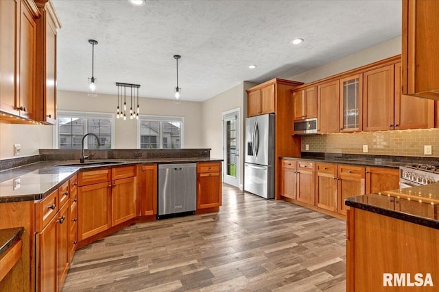 kitchen with brown cabinets, stainless steel appliances, a sink, and a peninsula