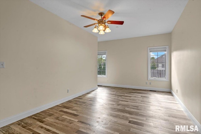 empty room with a ceiling fan, baseboards, vaulted ceiling, and wood finished floors