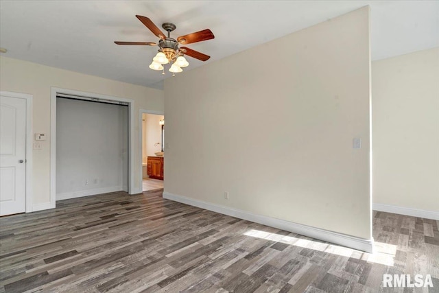 unfurnished bedroom featuring baseboards, ceiling fan, wood finished floors, and a closet