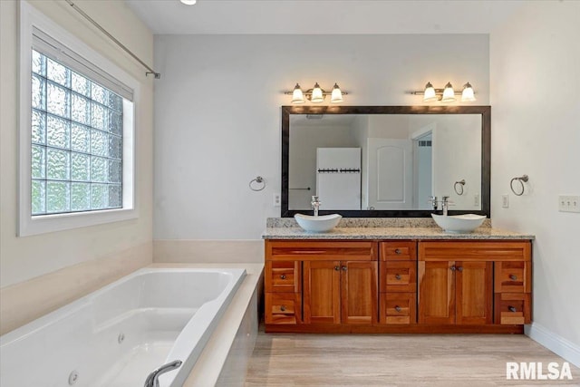 bathroom featuring double vanity, a sink, and a jetted tub