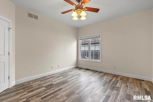 unfurnished room with baseboards, a ceiling fan, wood finished floors, and visible vents